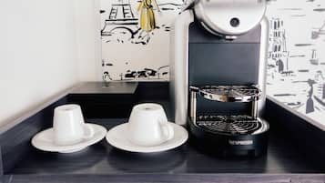 A Nespresso coffee machine on a countertop with two white cups and saucers.