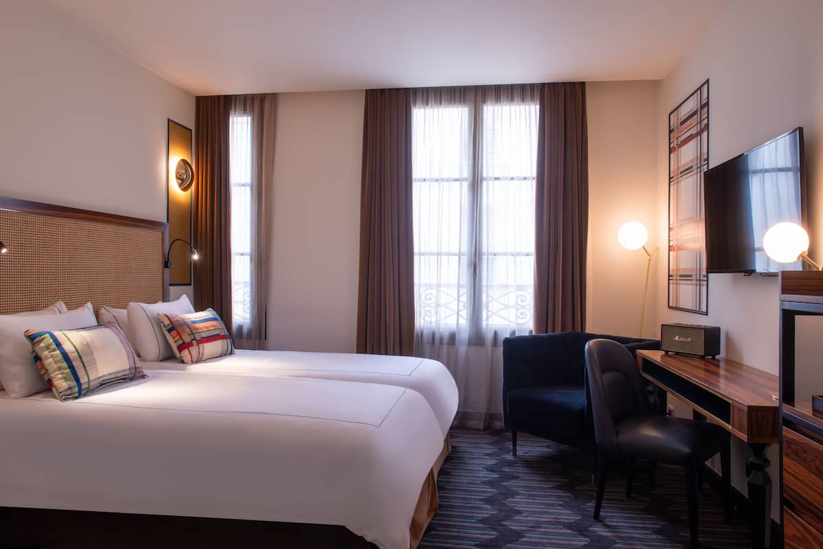 Une chambre d’hôtel avec un grand lit, un bureau, une chaise et un téléviseur.