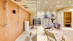 A modern gym with exercise equipment, a shower area, and a reception desk. - Mom’Art Hotel (Paris)