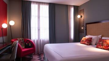 Una habitación de hotel con una cama, un escritorio, una silla y un sillón rojo.