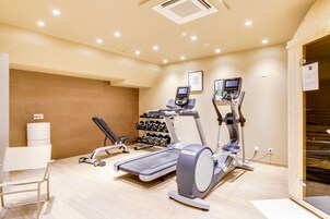 A gym with treadmills, elliptical machines, and dumbbells.