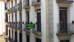 Un edificio con varios balcones, cada uno adornado con plantas en macetas y un letrero que dice "PENSION ABITES".