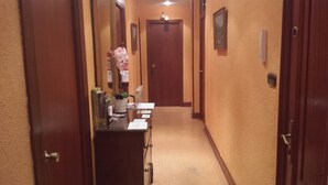 Un pasillo de hotel con puertas de madera, un mostrador de recepción con una planta y un tablón de anuncios.