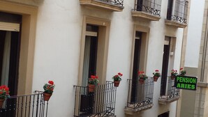 Una hilera de balcones con macetas y un letrero que dice "PENSION ARIES".