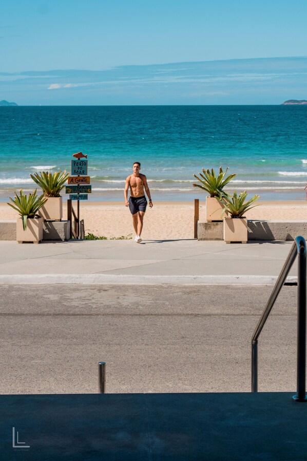 Un homme se promène sur une plage, tenant une pancarte sur laquelle on peut lire : « Puerto Mar A Gente ».