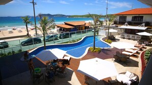 A resort with a swimming pool, beach view, and outdoor seating area. - Paradiso Pero Praia Hotel (Cabo Frio)