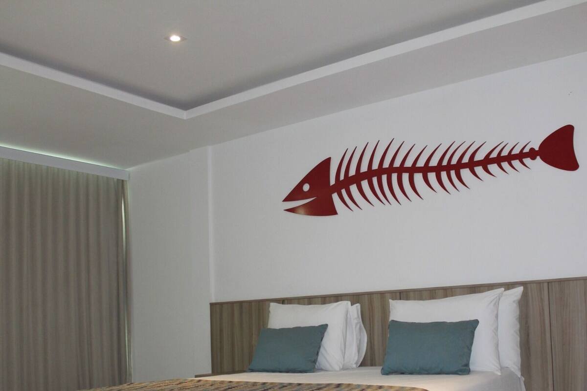 Une chambre d’hôtel avec un lit, une tête de lit et une décoration murale représentant le squelette d’un poisson.