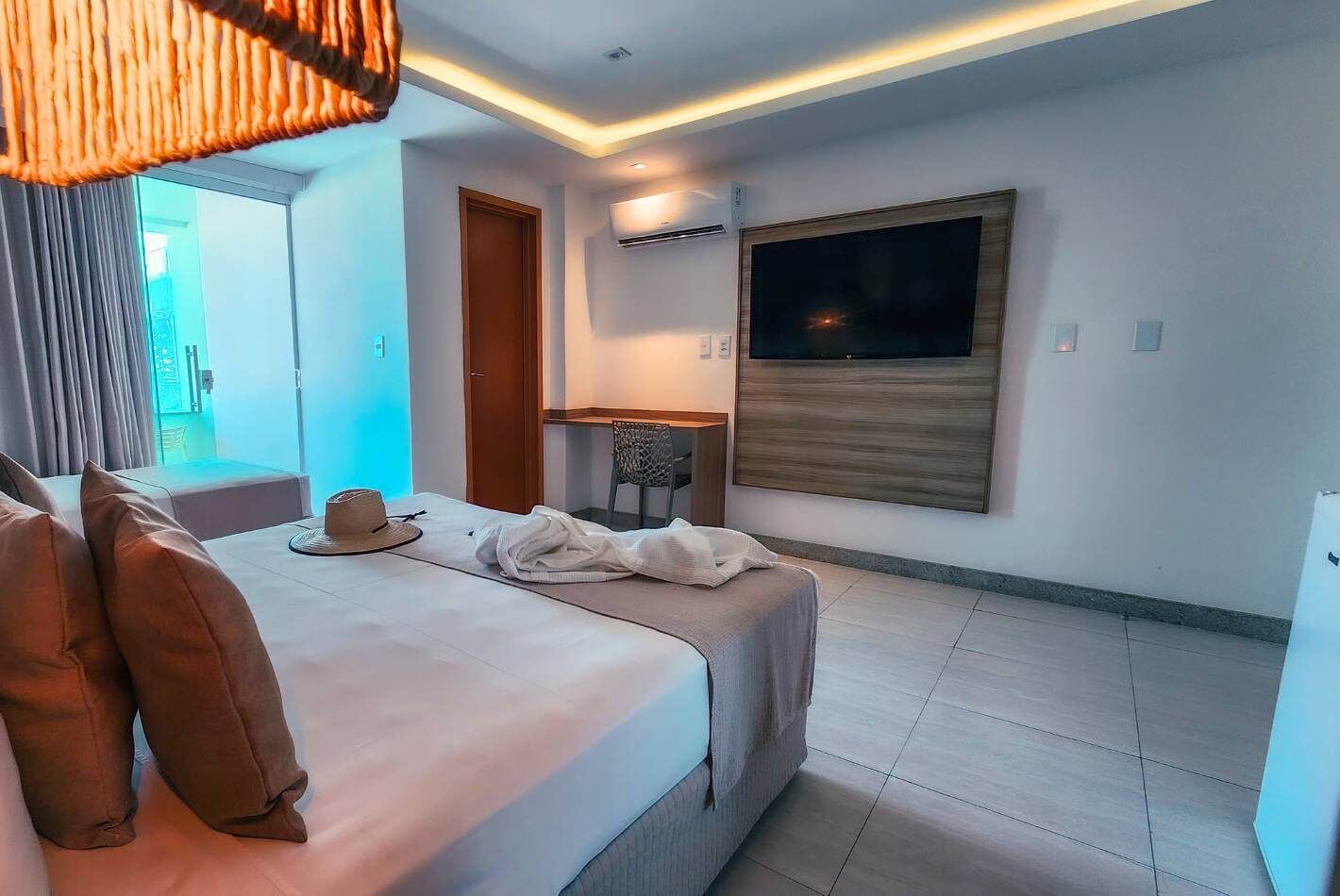A modern hotel room with a bed, a desk, and a TV.