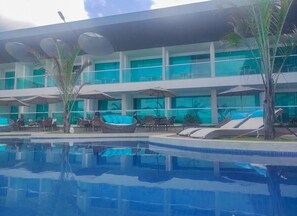 Un hotel moderno con piscina, sillones de descanso y sombrillas.