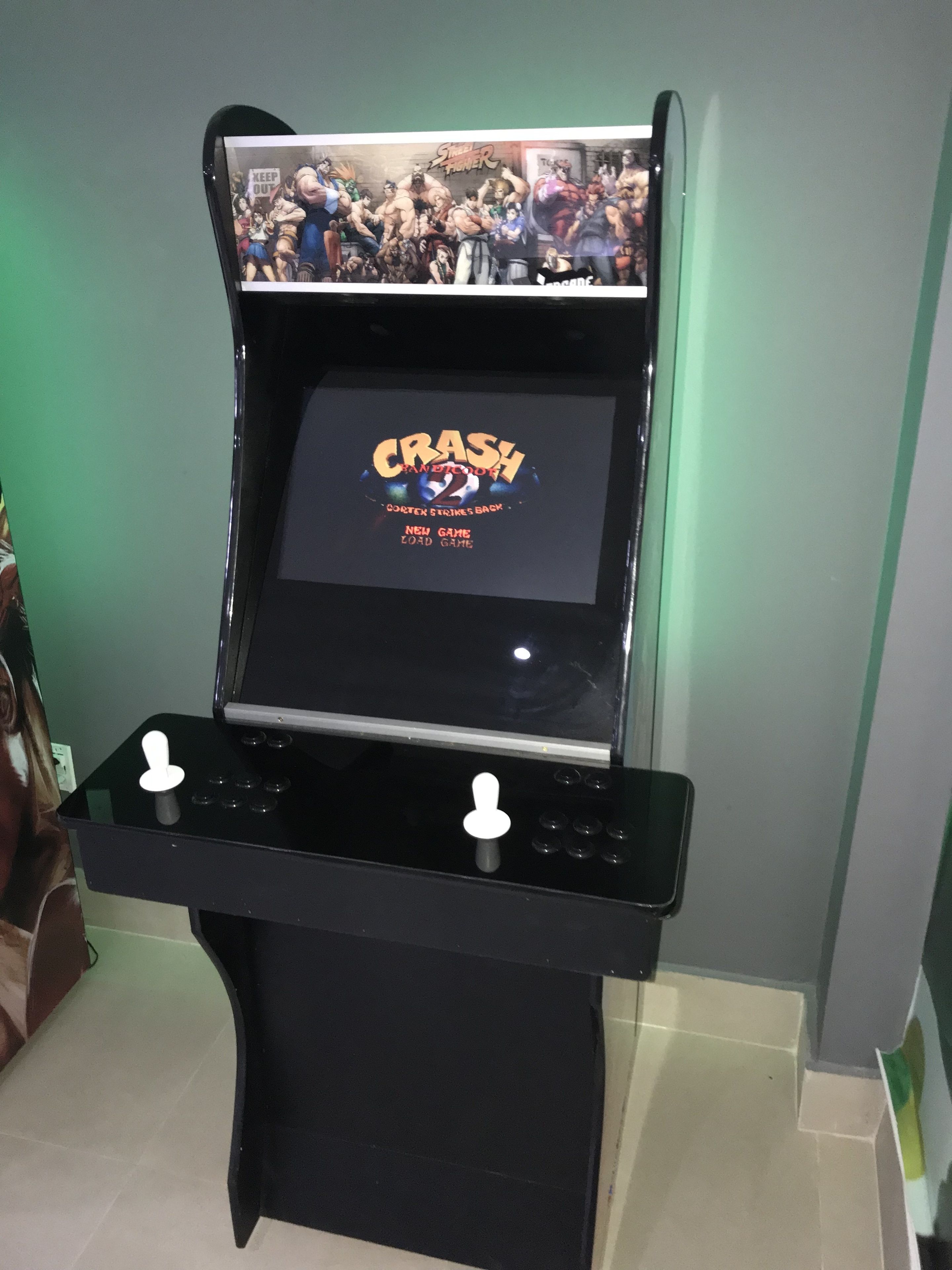 Une borne d’arcade de jeu vidéo dont l’écran affiche les titres « CRASH » et « Cortex Strikes Back ».