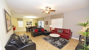 A living room with a black leather sofa, a red sofa, a coffee table, and a ceiling fan. - Providence 2323EVDIL (Davenport)
