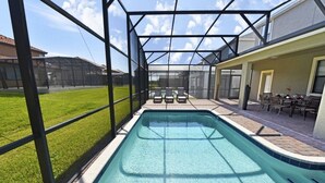 A swimming pool with a glass enclosure, surrounded by a patio area with chairs and a table. - Providence 2323EVDIL (Davenport)