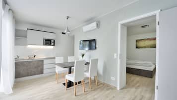 Una cocina moderna con armarios blancos, un microondas y un comedor con mesa y sillas.