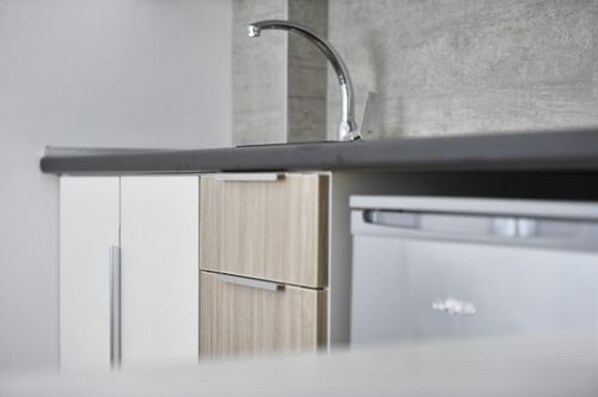 A modern kitchen with a stainless steel sink, wooden cabinets, and a built-in dishwasher. - Villa Oliver 2 Siófok (Siófok)