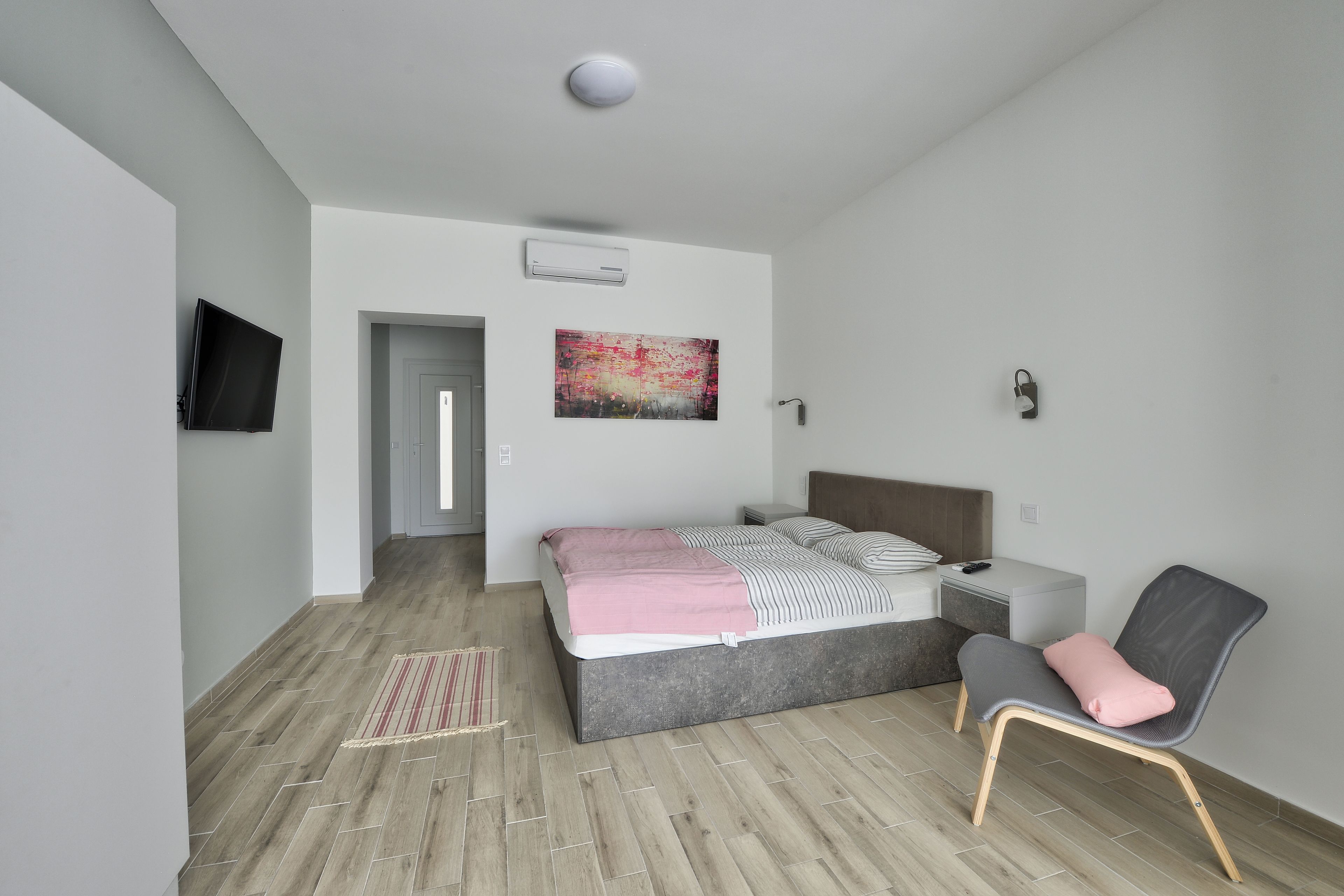 A modern bedroom with a bed, bedside table, chair, and artwork on the wall.