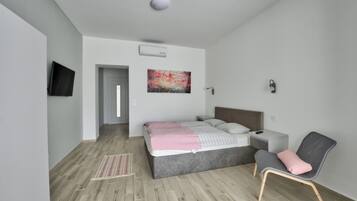 A modern bedroom with a bed, bedside table, chair, and artwork on the wall.