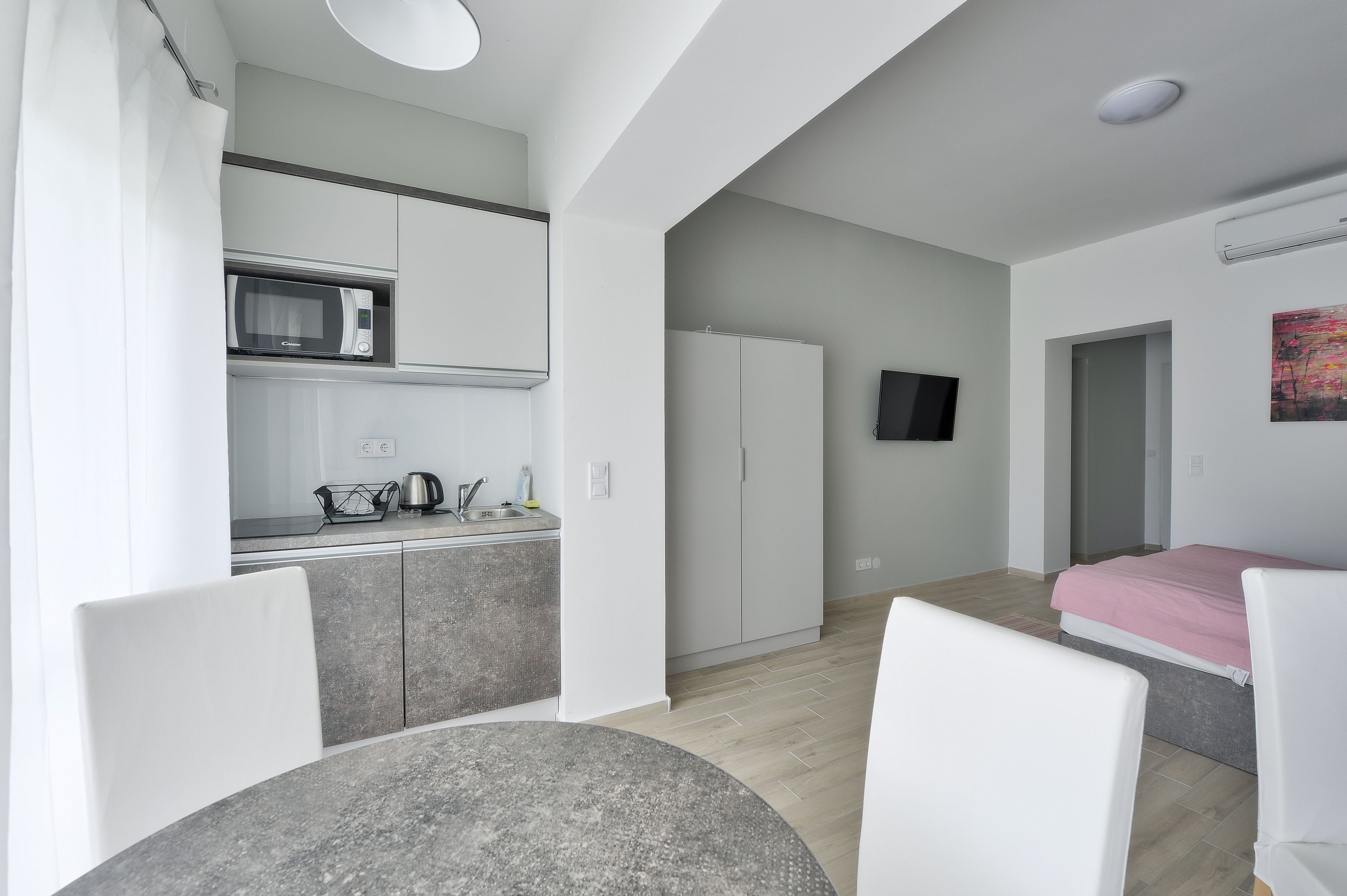 A modern, well-lit room with a kitchen area, a dining table, and a bed.