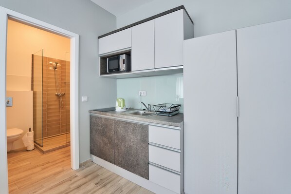 Una cocina moderna con microondas, lavamanos y armarios.
