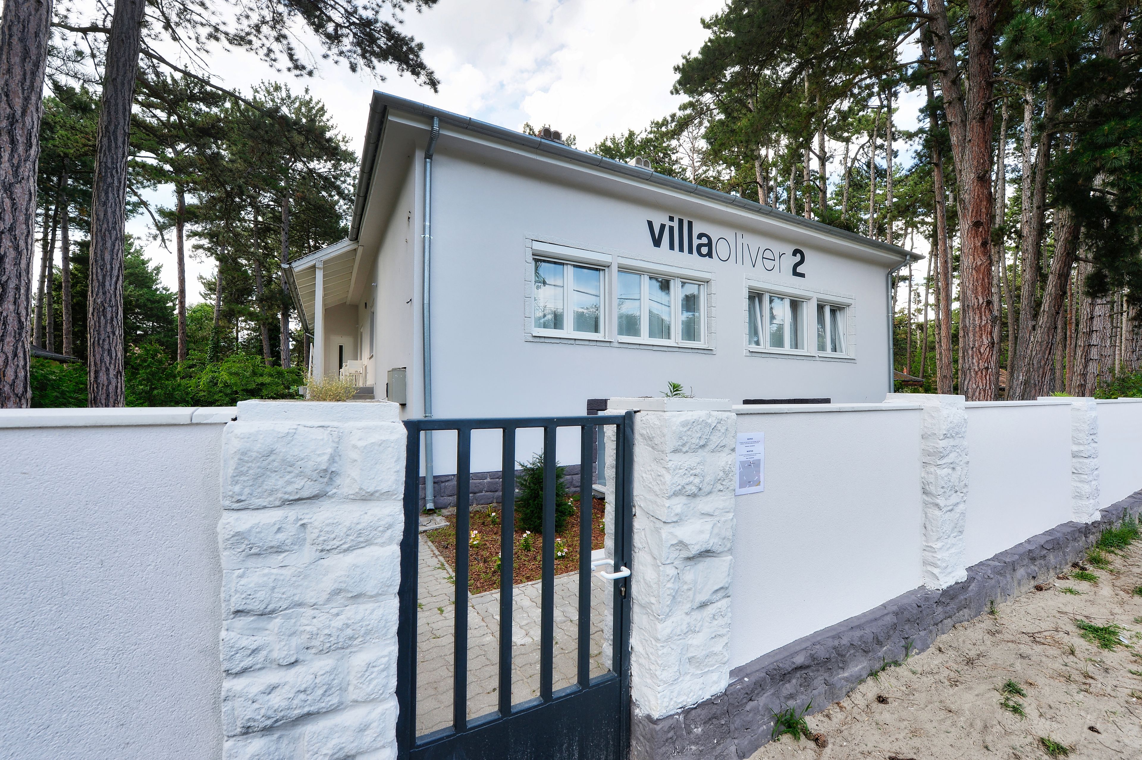 Eine Villa namens "villa oliver 2" mit einer Steinmauer und einem schwarzen Tor.