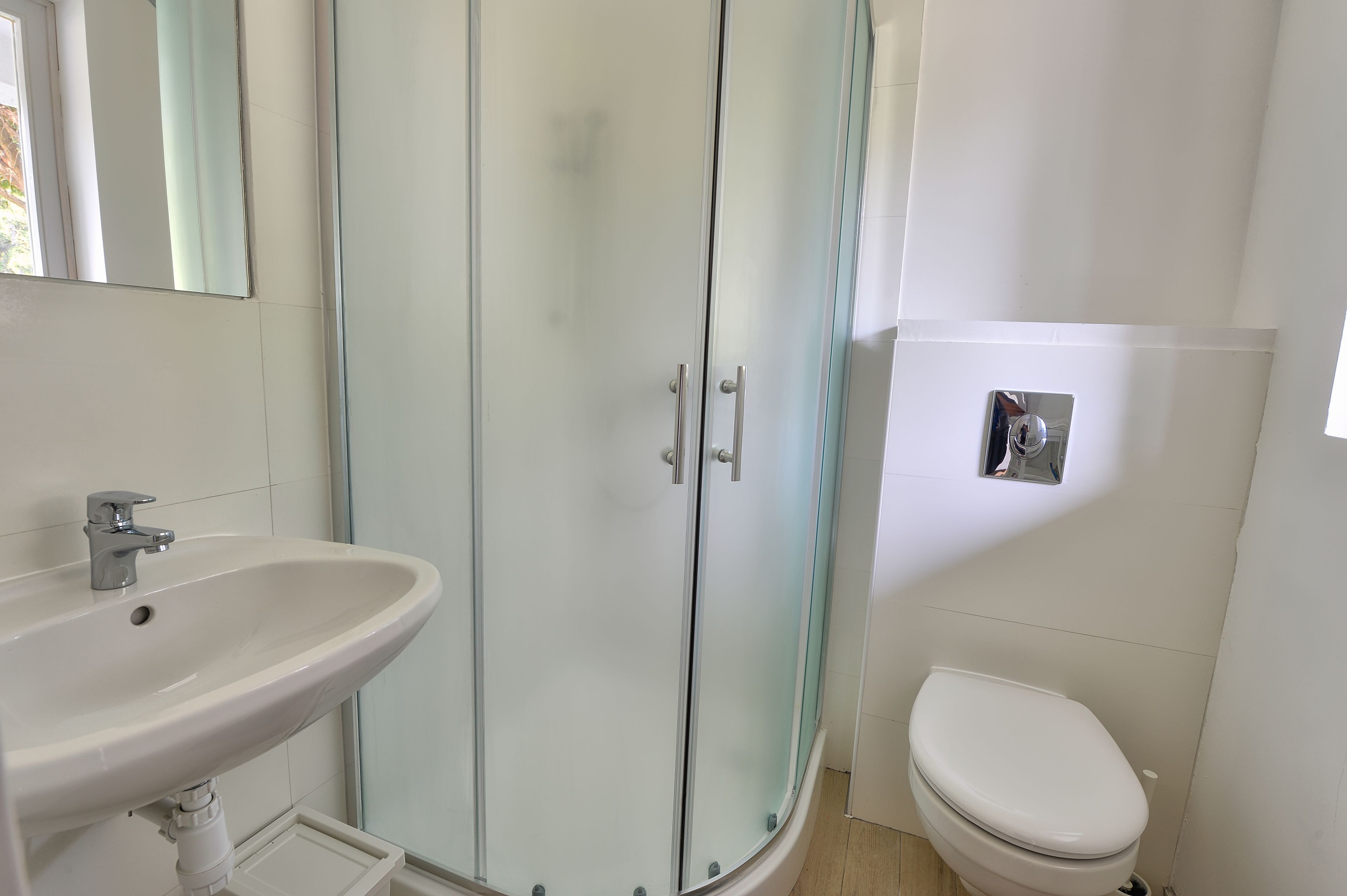 Une salle de bain avec une douche à parois de verre, un lavabo blanc et des toilettes.