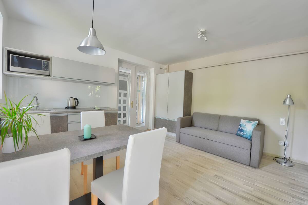 A modern kitchen with a microwave, a kettle, and a dining area with a table and chairs.