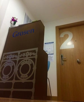 Une pièce avec une porte en bois portant le numéro 2, une enseigne fixée au mur avec l’inscription « GroSen », et une petite plante en pot accrochée au mur.