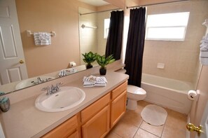 A bathroom with a sink, mirror, toilet, and bathtub.