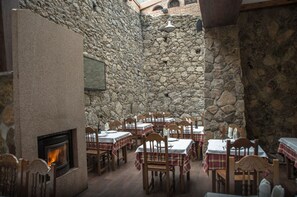 A stone-walled dining area with tables and chairs, a fireplace, and a stone ceiling. - Hotel Casa Beletri (Bejar)