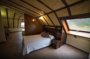 A bedroom with a large bed, wooden headboard, a nightstand, and a window with a view of greenery. - Hotel Casa Beletri (Bejar)