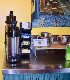 A coffee machine, a hot chocolate dispenser, and a sign for orange juice on a counter. - Green Tortoise Hostel Seattle (Seattle)
