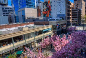 A multi-story building with a glass facade, a large mural on the side, and a street with cherry blossoms in the foreground. - Green Tortoise Hostel Seattle (Seattle)