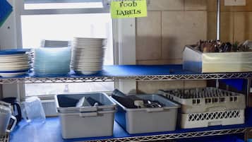 Un área de cocina con estantes que contienen platos, tazones y recipientes para almacenar alimentos.