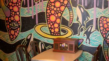 Interior de restaurante con un mural colorido, una mesa con sillas y una radio antigua.