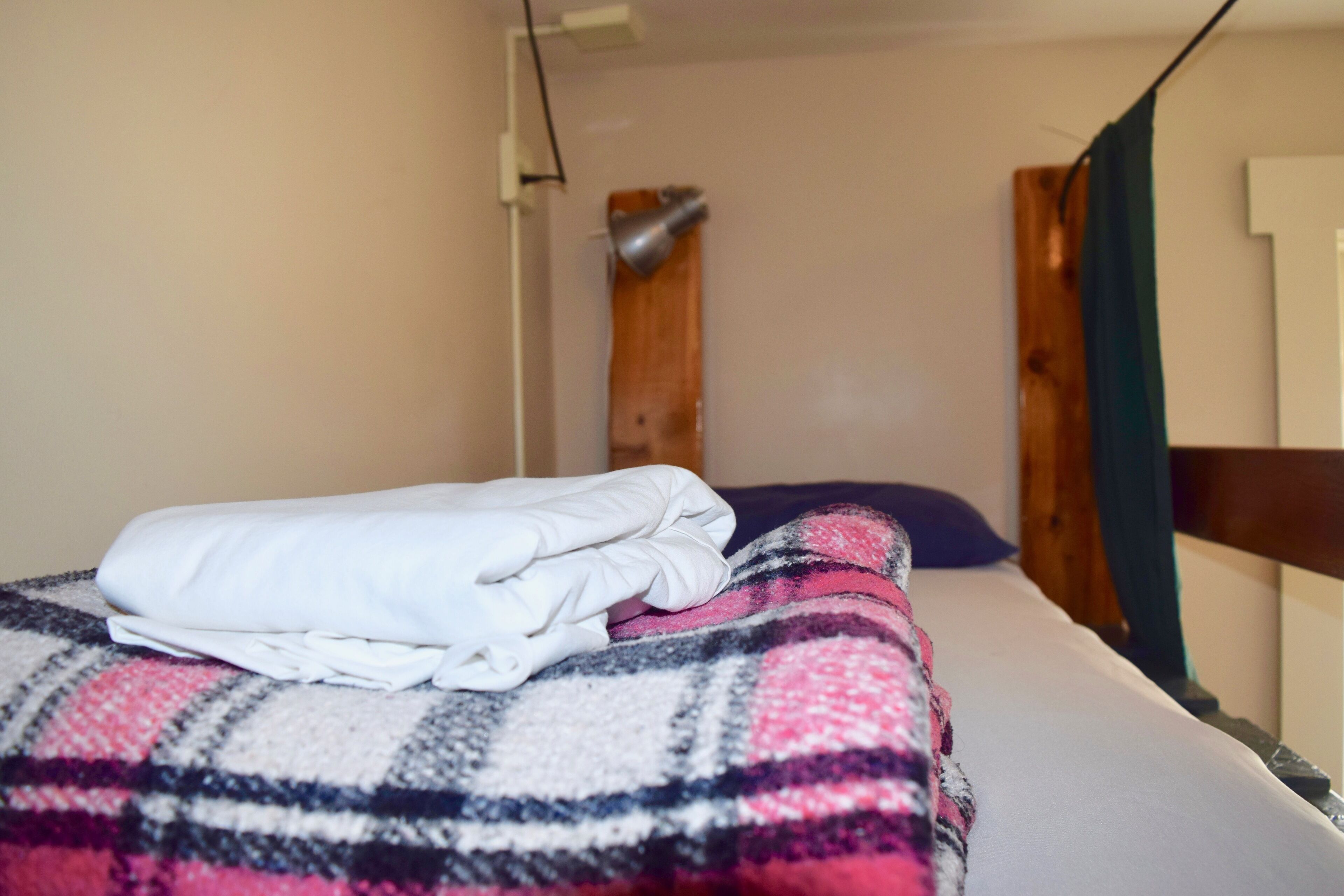 A bed with a plaid blanket and a folded white towel.
