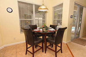 A dining area with a round table, four chairs, a clock, and a window with blinds. - 538 BRIG (Davenport)