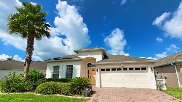 A single-story house with a garage, surrounded by well-maintained landscaping, including a palm tree and shrubs. - 1842 NHD (Davenport)