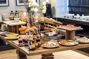 A buffet with various food items including pastries, muffins, and pizza. - Cyan Soho Neuquen Hotel (Neuquén)