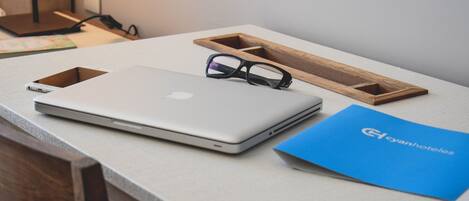 A laptop, a pair of glasses, and a blue folder on a table.