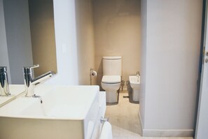 A modern bathroom with a large sink, toilet, and bidet. - Cyan Soho Neuquen Hotel (Neuquén)