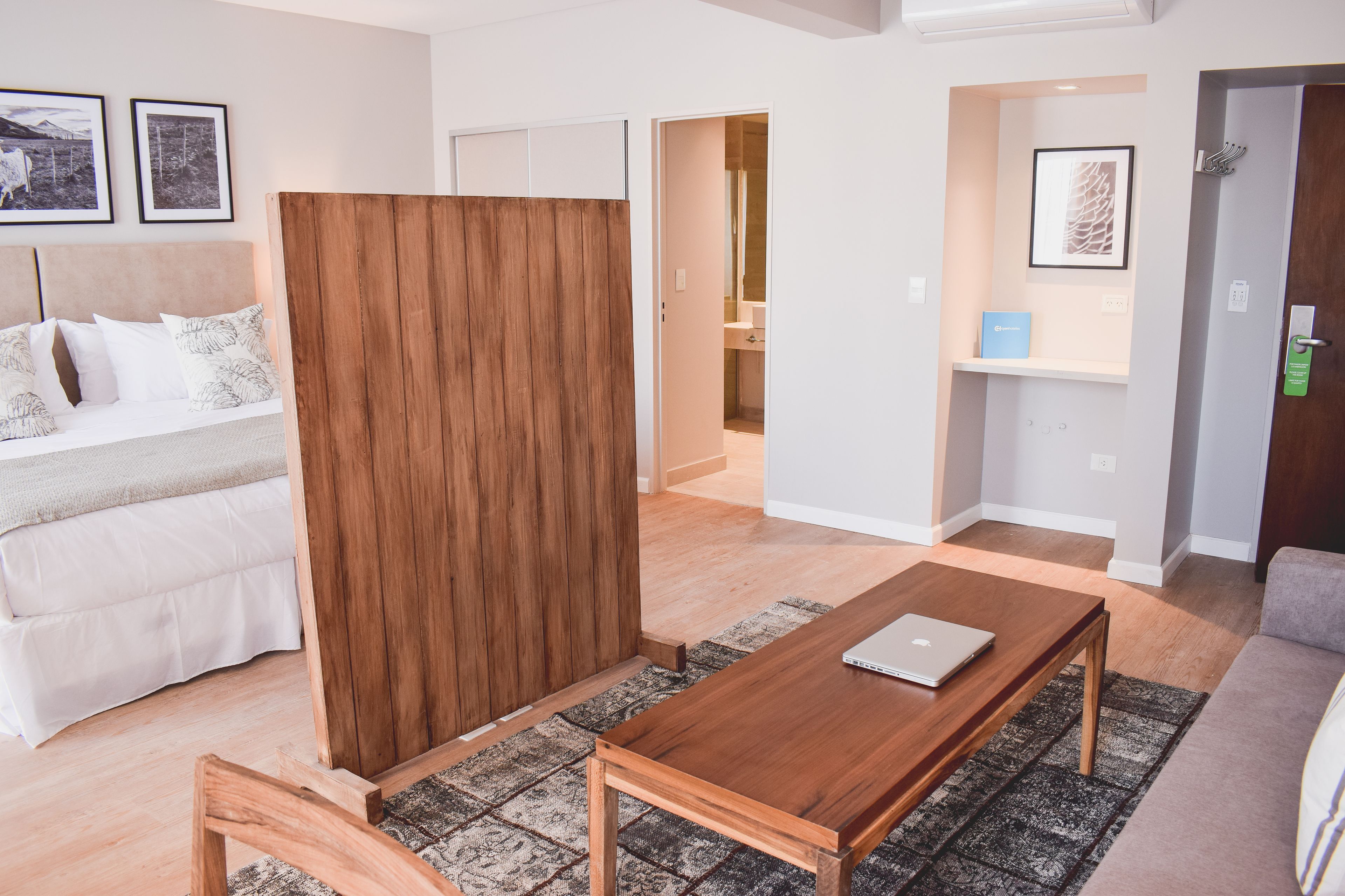A modern living room with a wooden coffee table, a sofa, and a bed with a headboard.