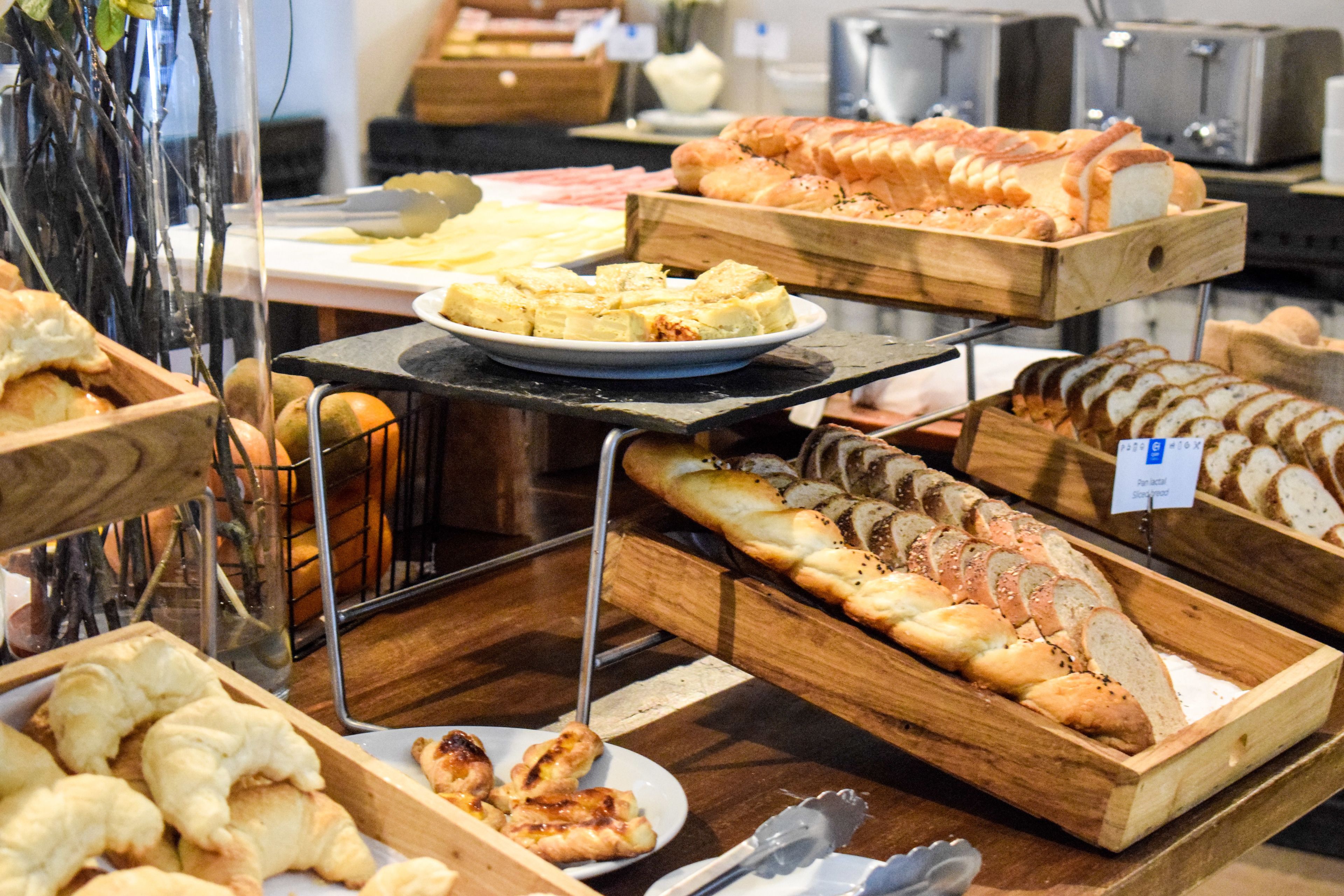 Een bakkerijvitrine met verschillende broden en gebak.