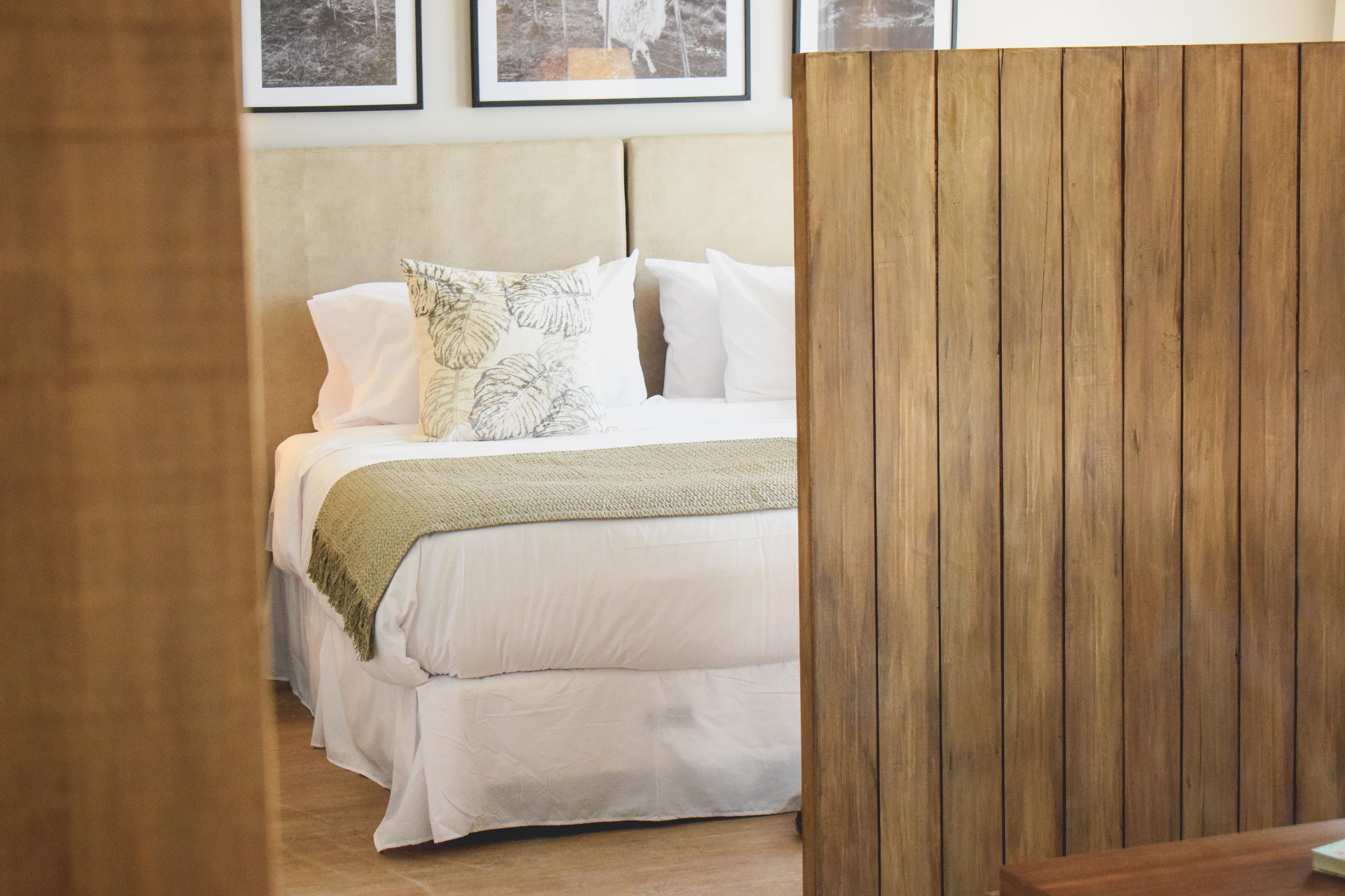 A bedroom with a bed, a wooden partition, and a framed picture on the wall.