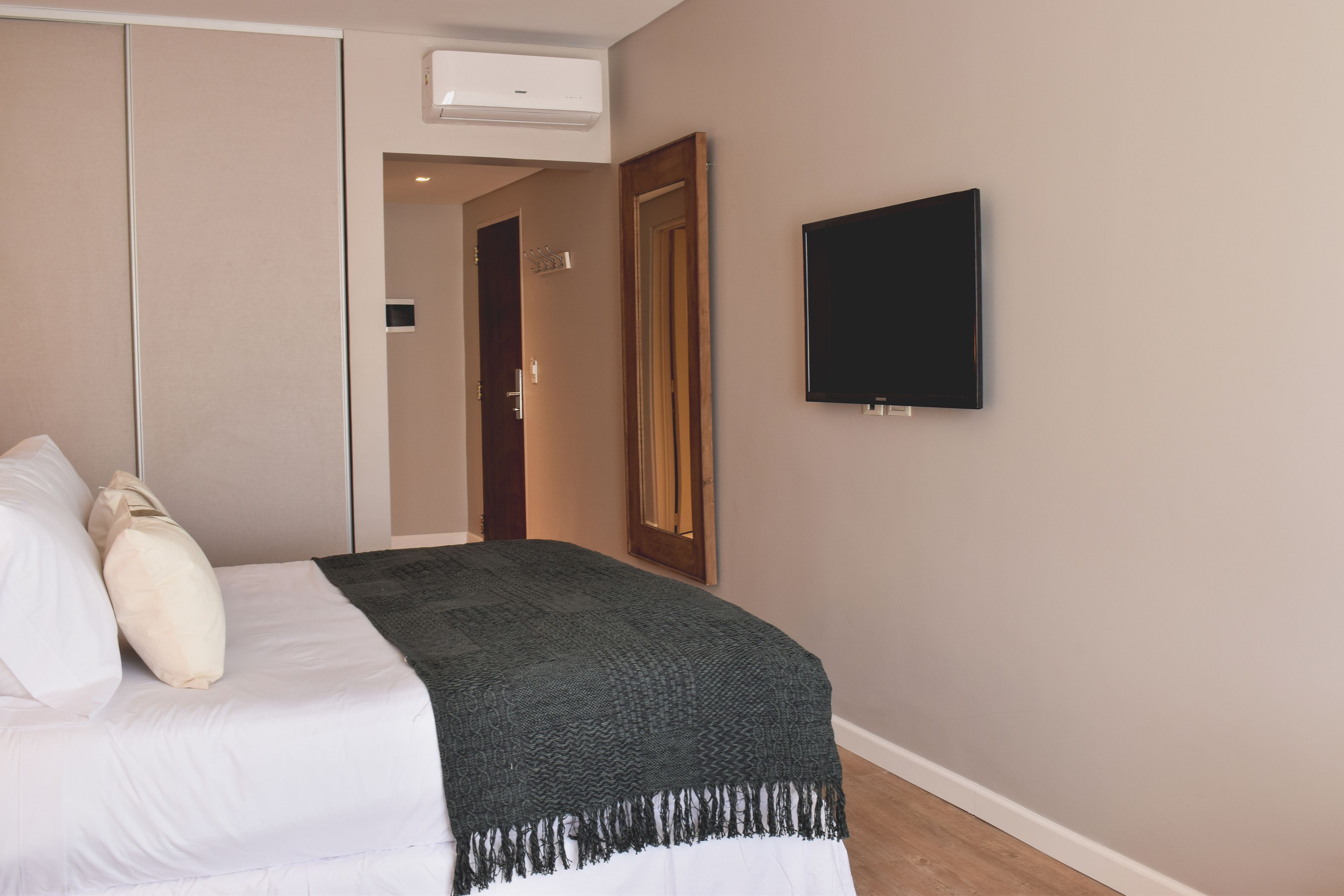 Una habitación de hotel con una cama, televisión y una puerta que da a otra habitación.