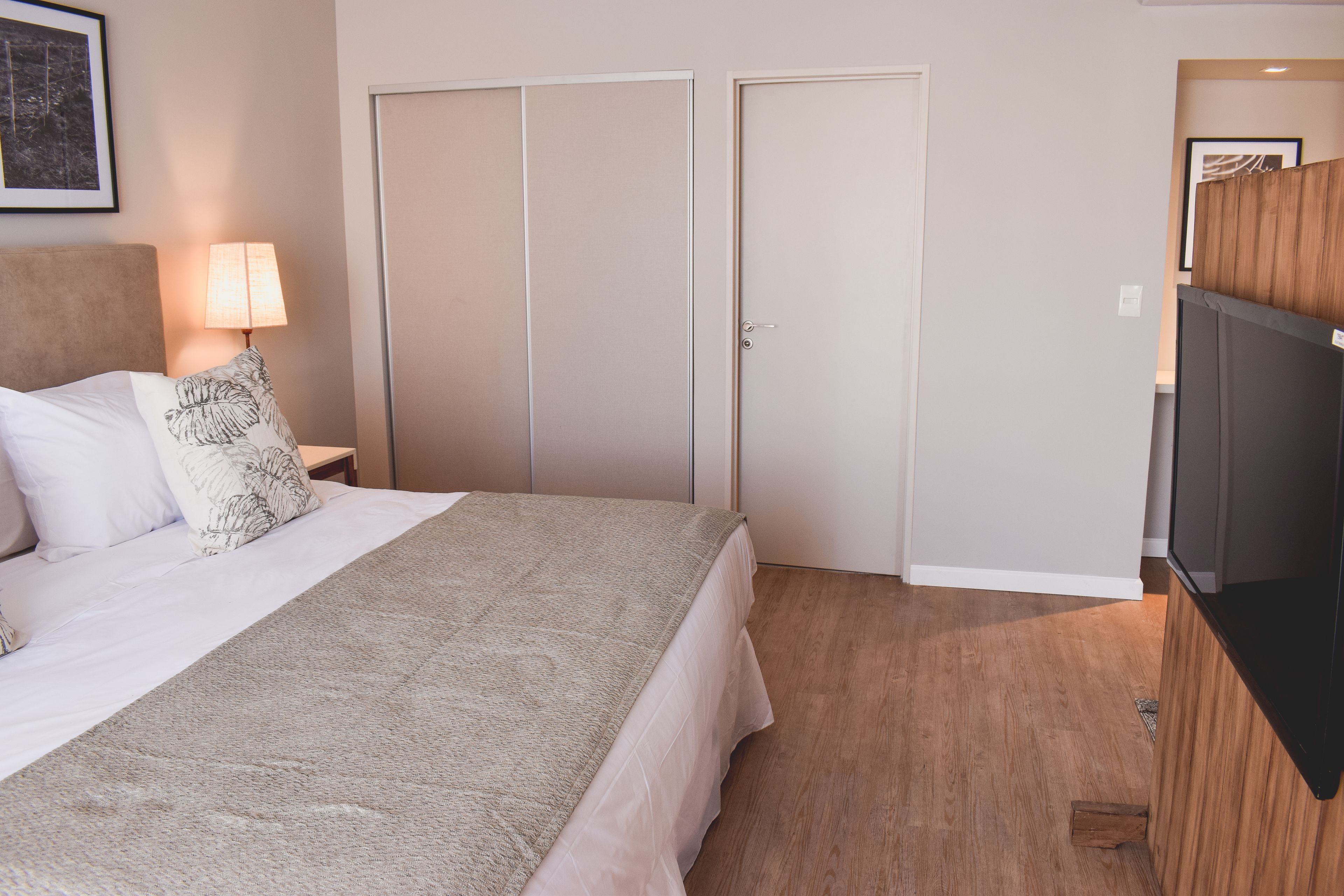 Een hotelkamer met een bed, een televisie, een kledingkast en een lamp.