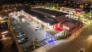 Un motel con estacionamiento, un túnel de lavado de autos y un edificio con toldo rojo.