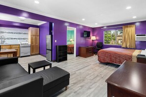 A compact hotel room with a kitchenette, a bed, a desk, and a TV. - Orange Villa Park Motel (Orange)