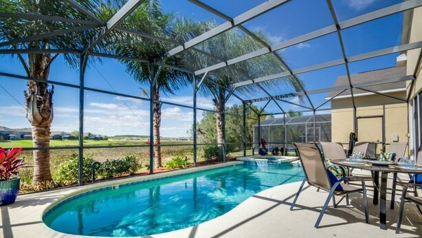 Una piscina interior con cerramiento de vidrio, rodeada de palmeras y vistas a un campo de golf.