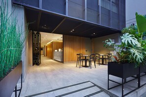 A modern indoor space with a reception area, seating, and potted plants.