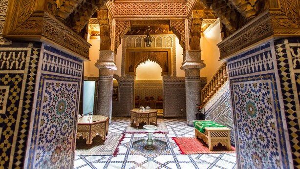 An ornate interior with intricate tile work, a central fountain, and a staircase leading to an upper level. - Riad Al Fassia Palace (Fes)