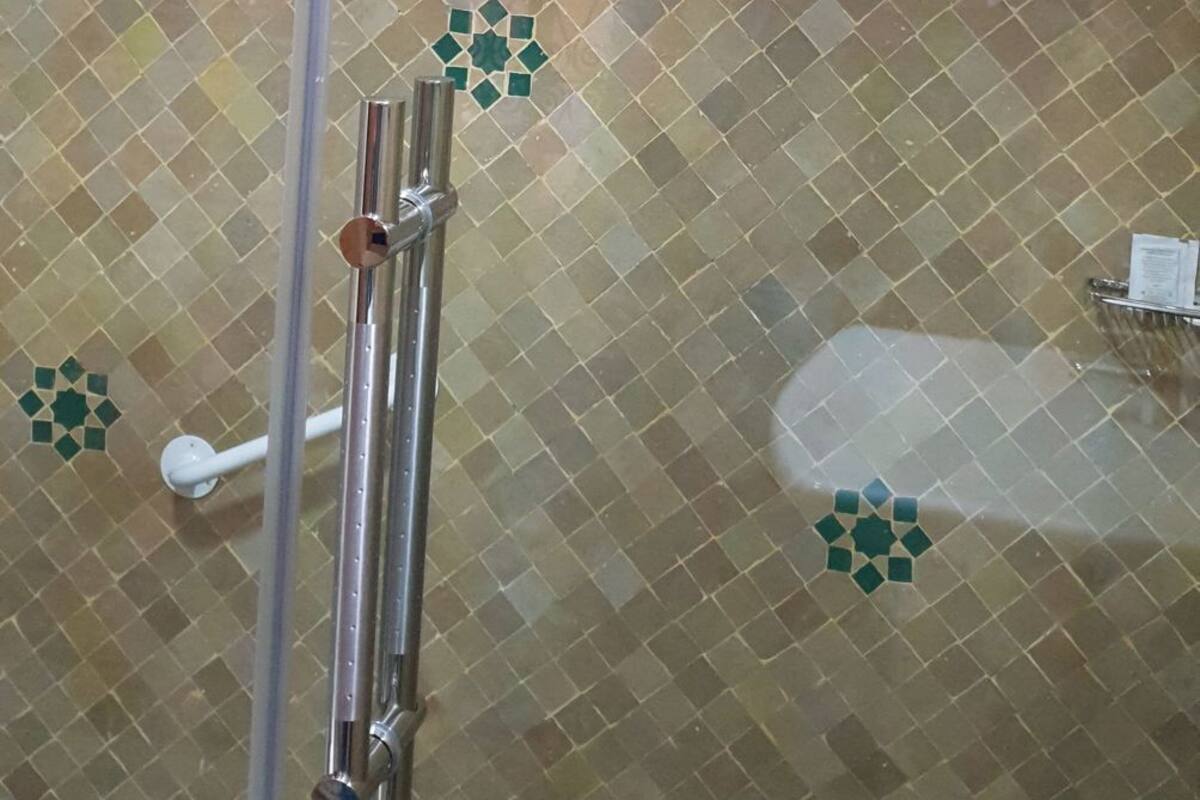 Box de chuveiro com design de azulejos estampados e porta de vidro.